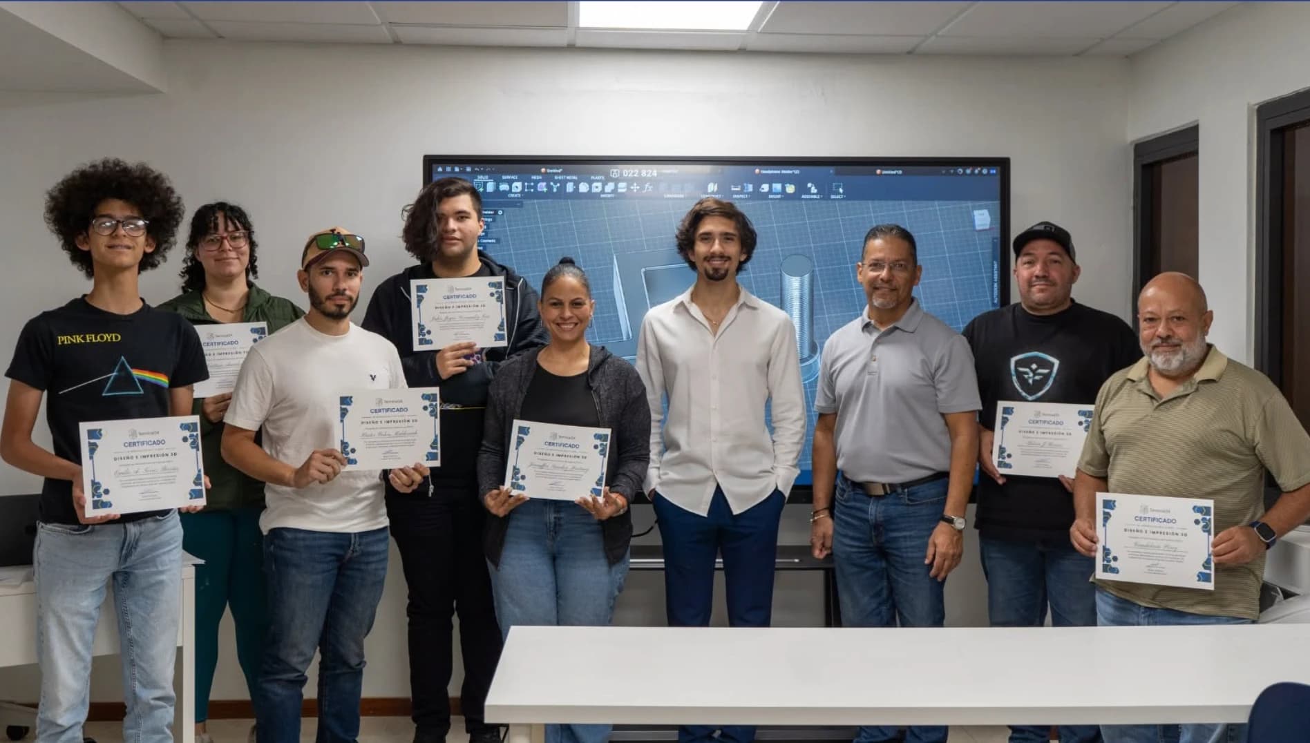 Estudiantes del curso de Diseño e Impresión 3D de Terminal34 con sus certificados frente a una pantalla con Autodesk Fusion