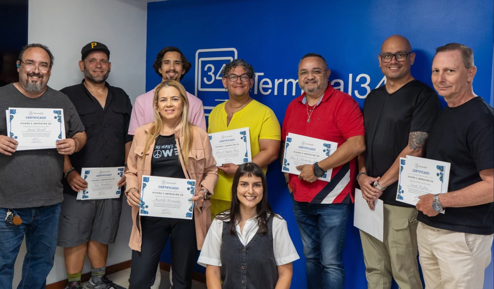 Graduados del curso de impresión 3D con sus certificados frente a la pared de Terminal34