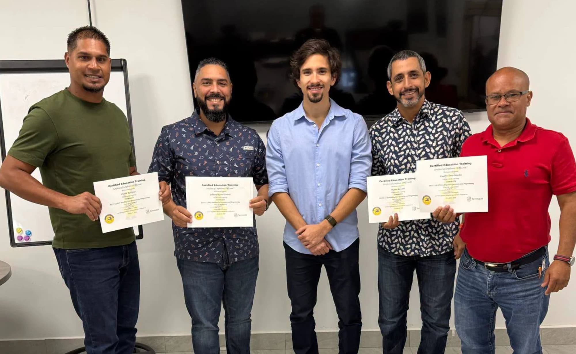 Cinco participantes del curso de Robótica Industrial FANUC con su instructor, mostrando sus certificados