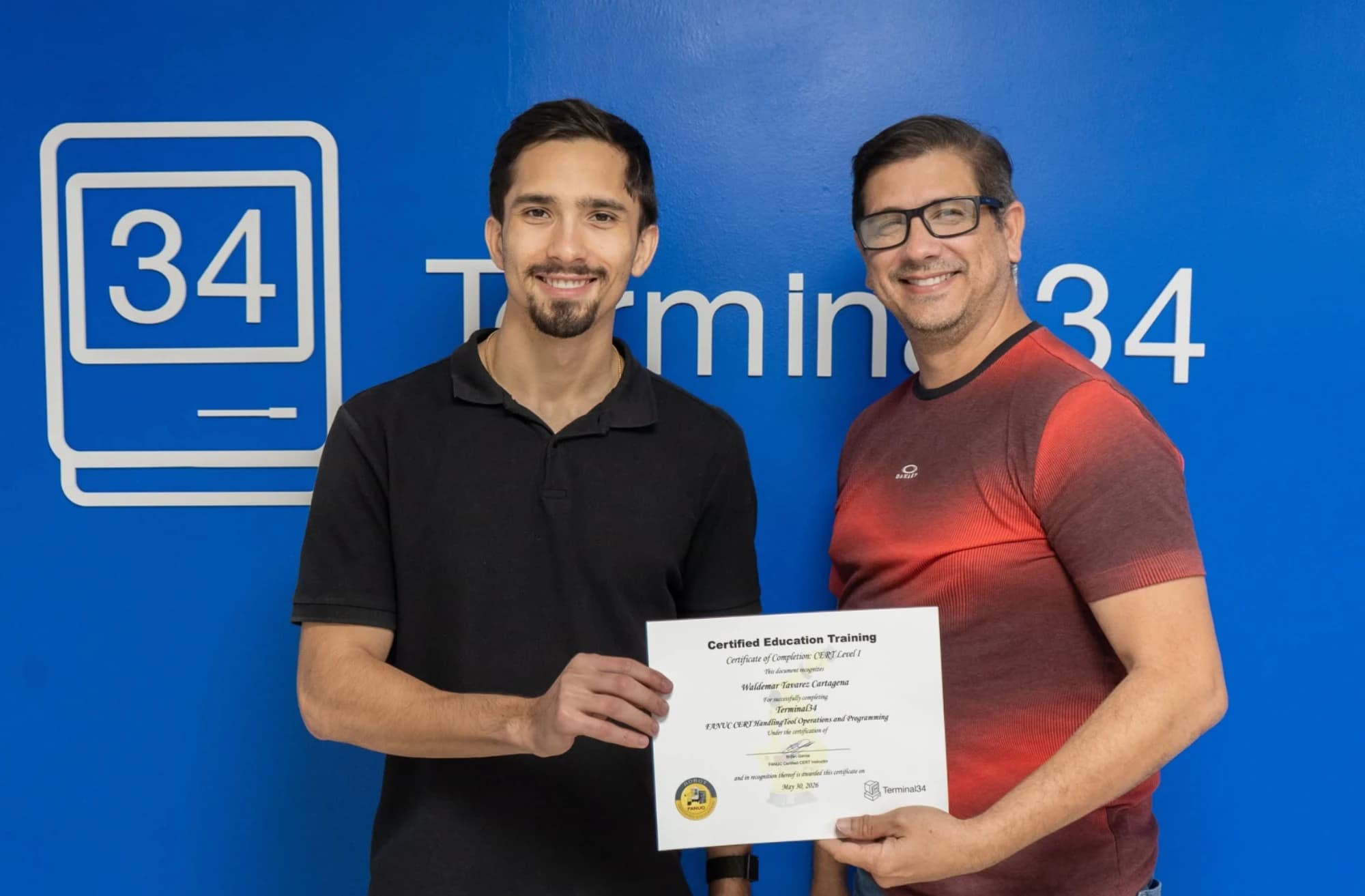 Graduado del curso de Robótica Industrial FANUC recibiendo su certificado de manos del instructor