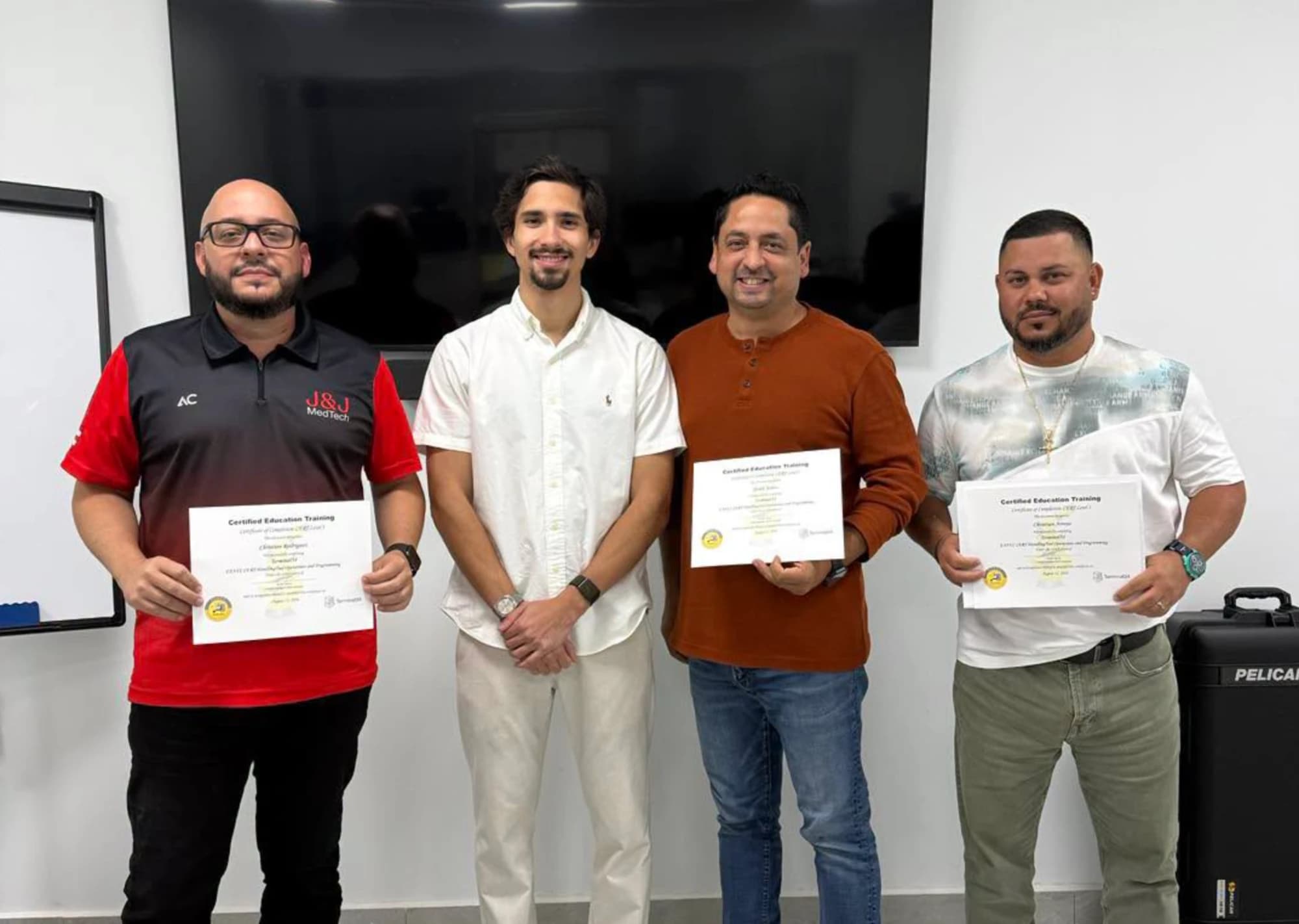 Cuatro participantes del curso de Robótica Industrial FANUC con su instructor, mostrando sus certificados