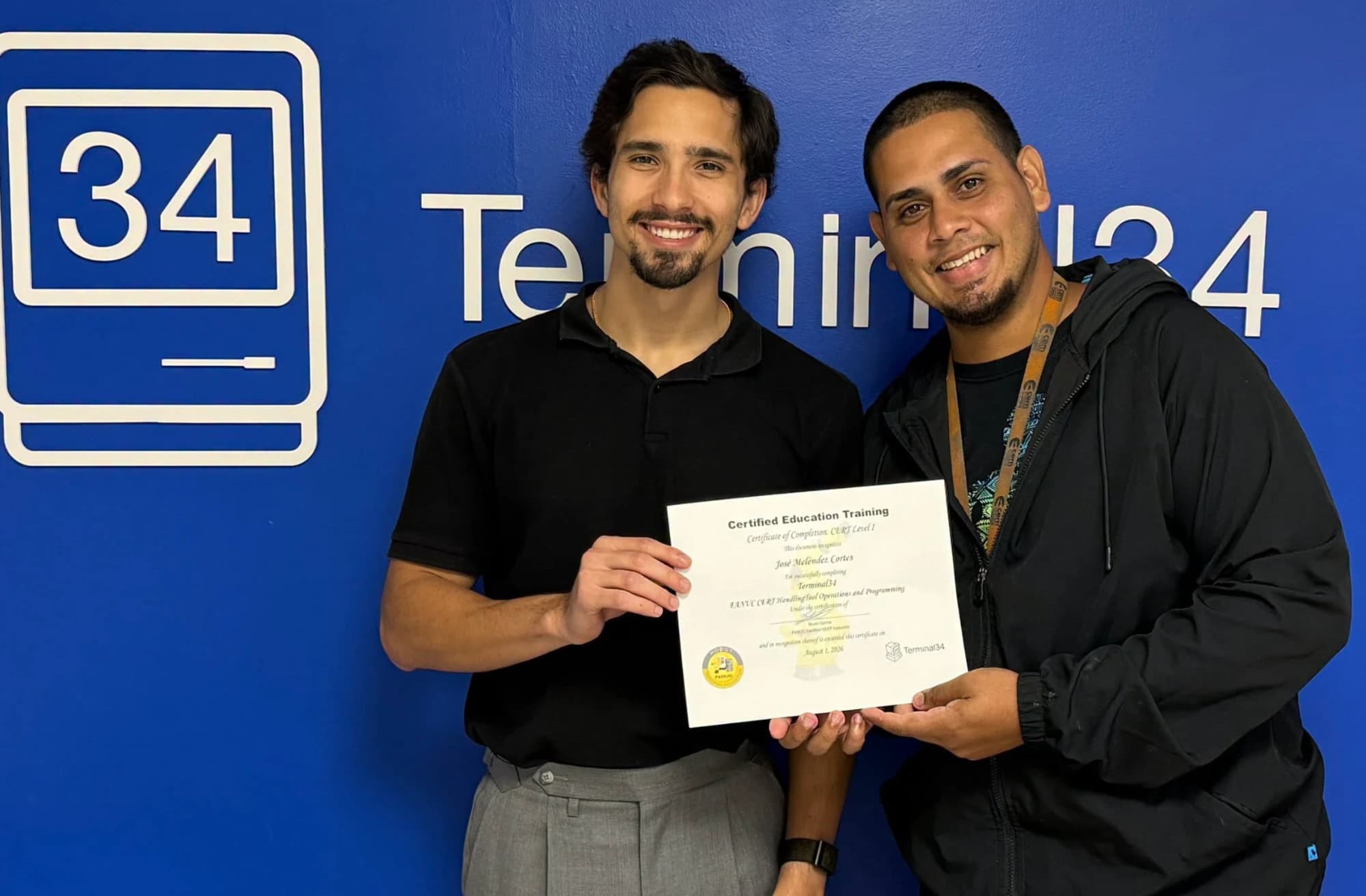 Graduado del curso de Robótica Industrial FANUC sosteniendo su certificado junto al instructor