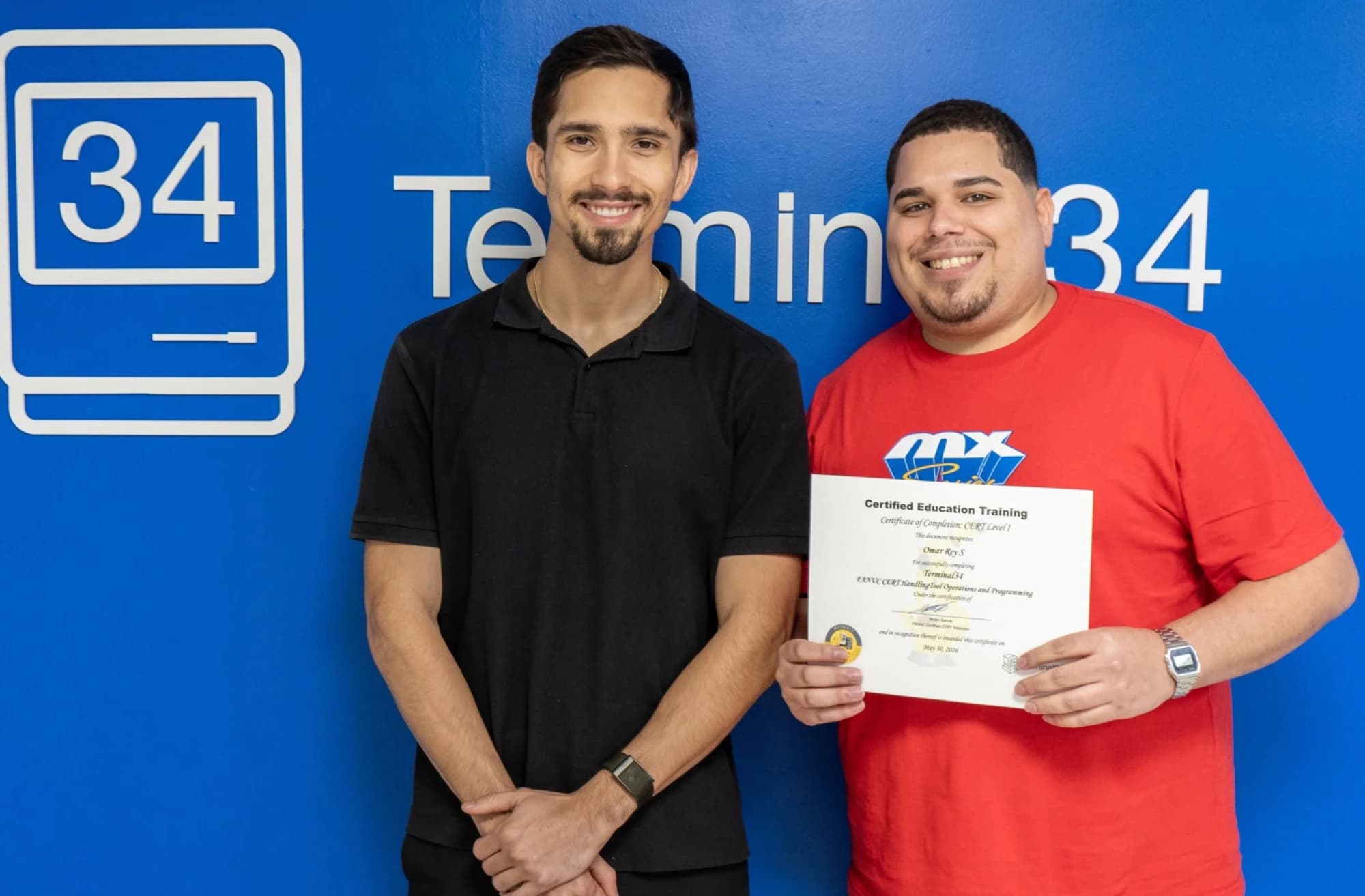 Graduado del curso de Robótica Industrial FANUC con camiseta roja y su certificado